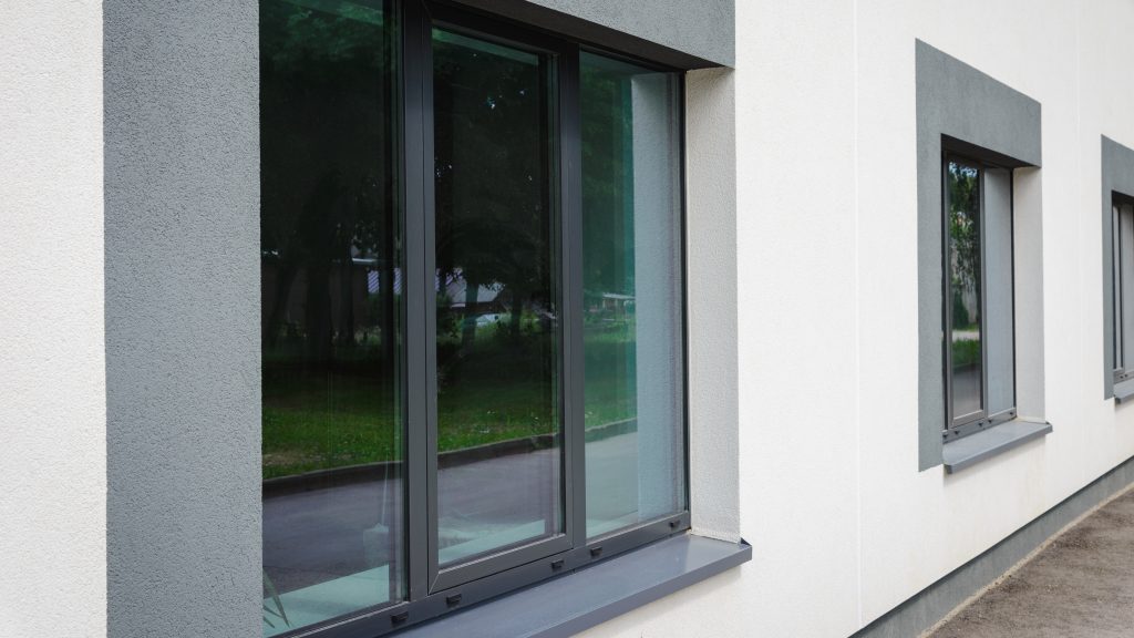 Moderne Aluminiumfenster mit schlankem Rahmenprofil in einer hellen Fassadenfläche eines Wohngebäudes.