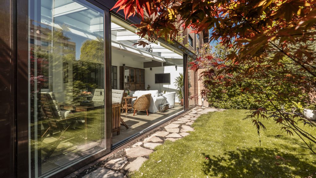 Moderner Wintergarten mit großflächigen Glas- und Schiebetürelementen als lichtdurchfluteter Übergang zwischen Wohnraum und Garten.